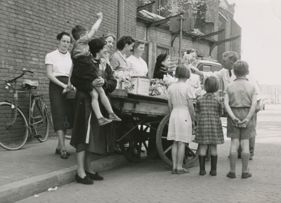 860986 Afbeelding van een groep vrouwen en kinderen en een Zuster Augustines rond de bloemenkar van Piet Schoonhoven ...